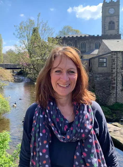 A picture of Helen Webb standing in the foreground with a river behind her